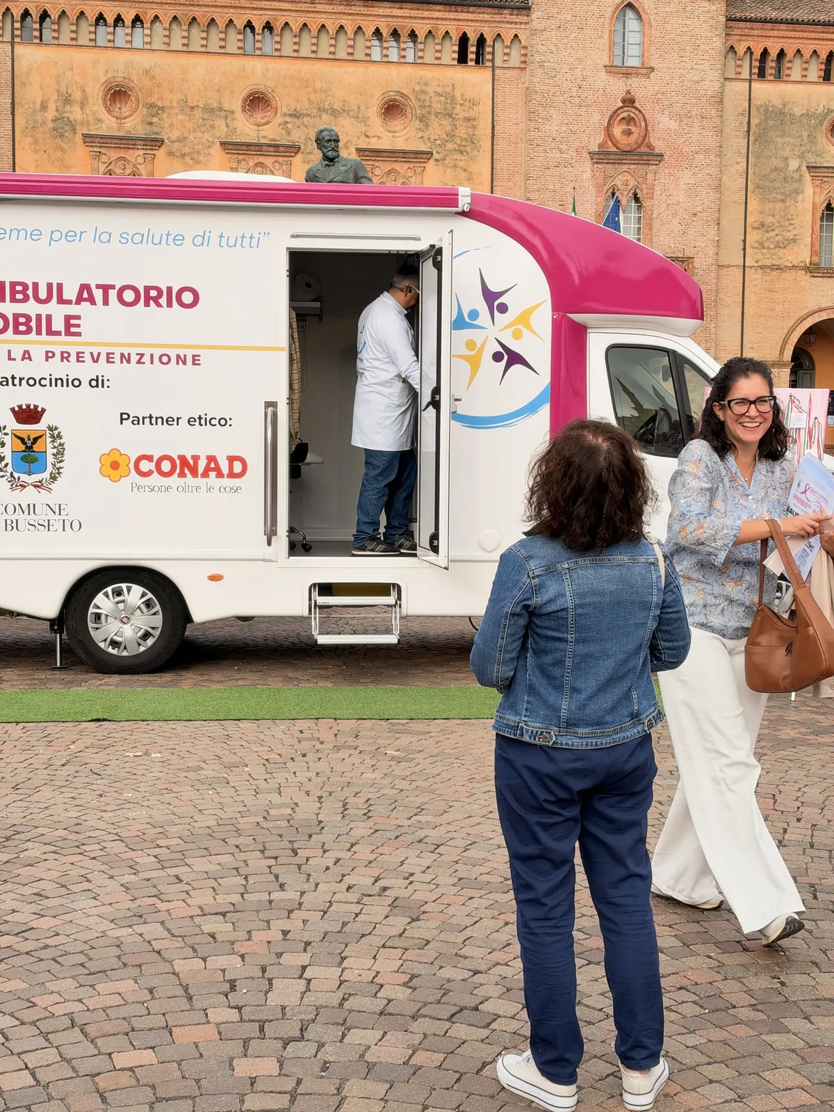 Due signore davanti alla porta aperta dell'ambulatorio mobile in Piazza Verdi