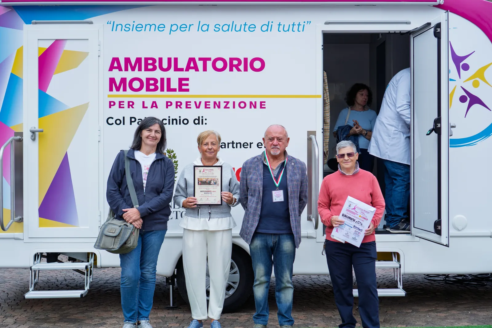 Partecipanti con l'attestato davanti all'ambulatorio mobile a Busseto