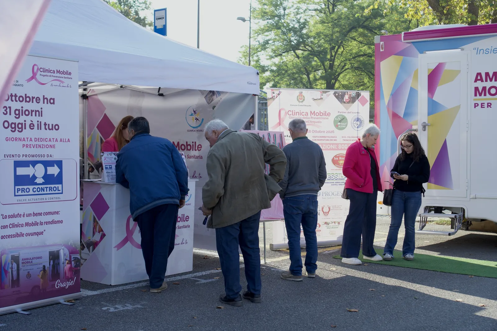 Persone al banco informazioni sotto il gazebo di Clinica Mobile a Castell'Arquato