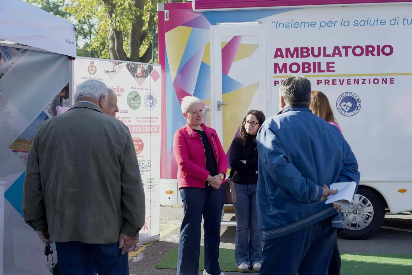 Due signore e un uomo chiacchierano in piazza davanti all'ambulatorio mobile