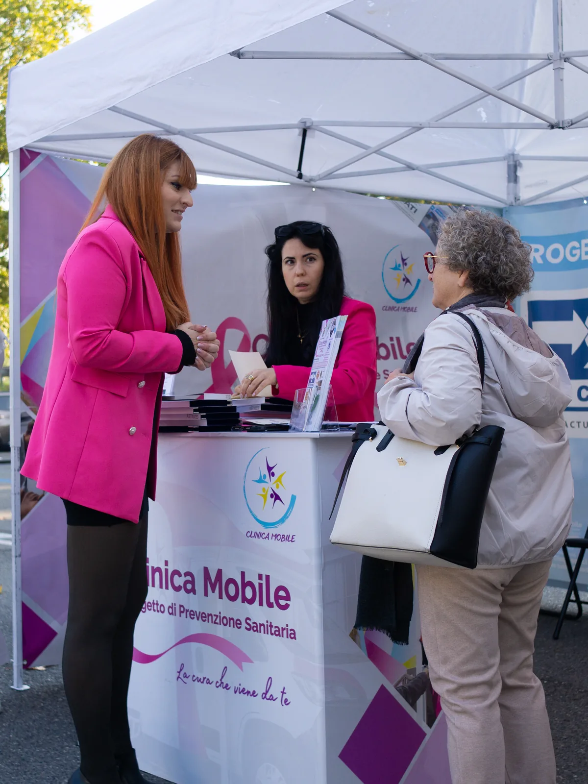 Operatrici della Clinica Mobile accolgono una cittadina al desk informativo a Castell'Arquato