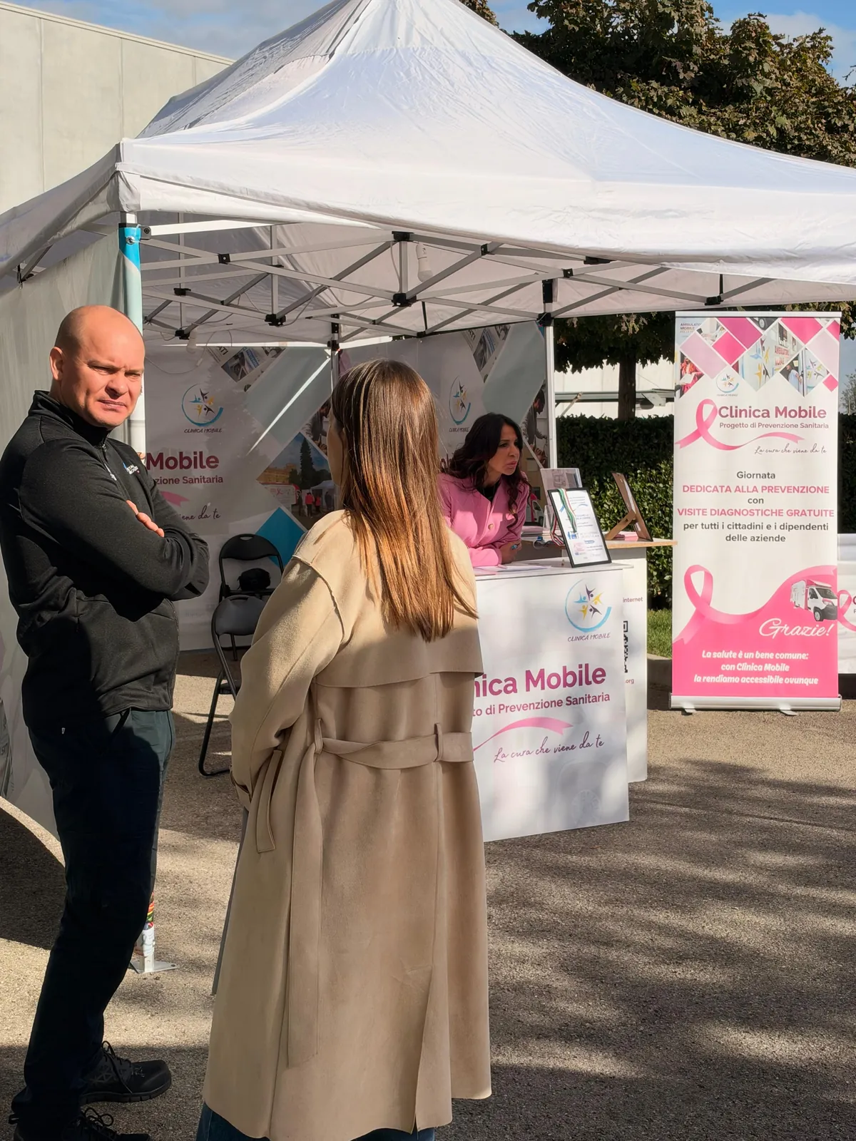 Un collega e una collega di FM al banco dell'accoglienza sotto il gazebo di Clinica Mobile