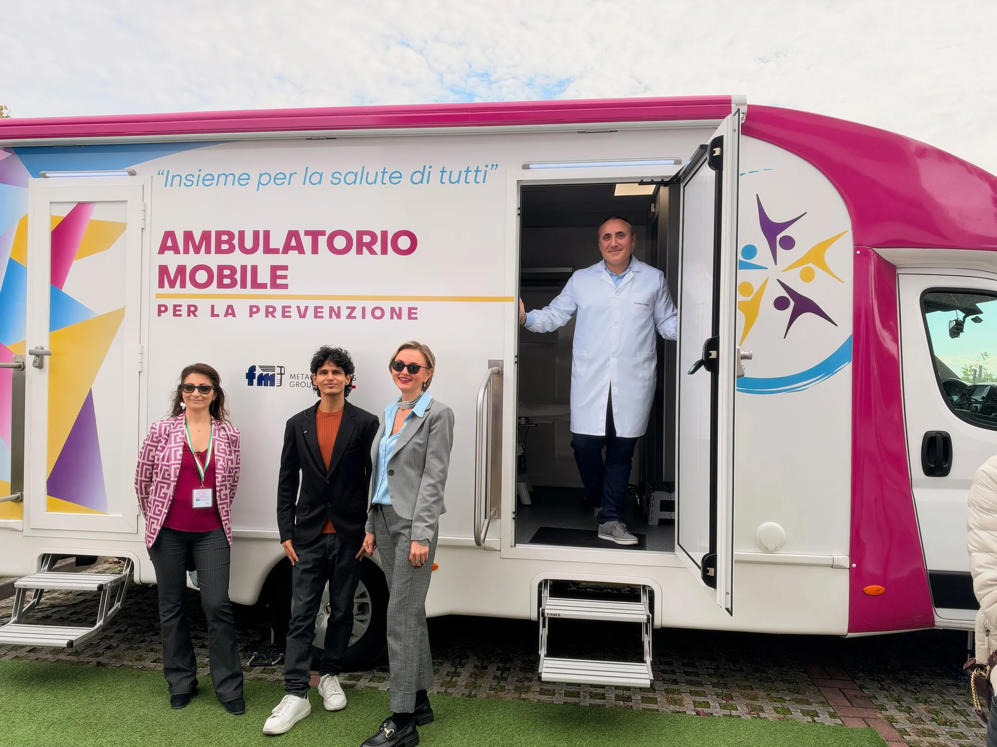 Tre colleghe di FM e il medico sulla porta dell'ambulatorio mobile nel piazzale dell'azienda a Reggio Emilia