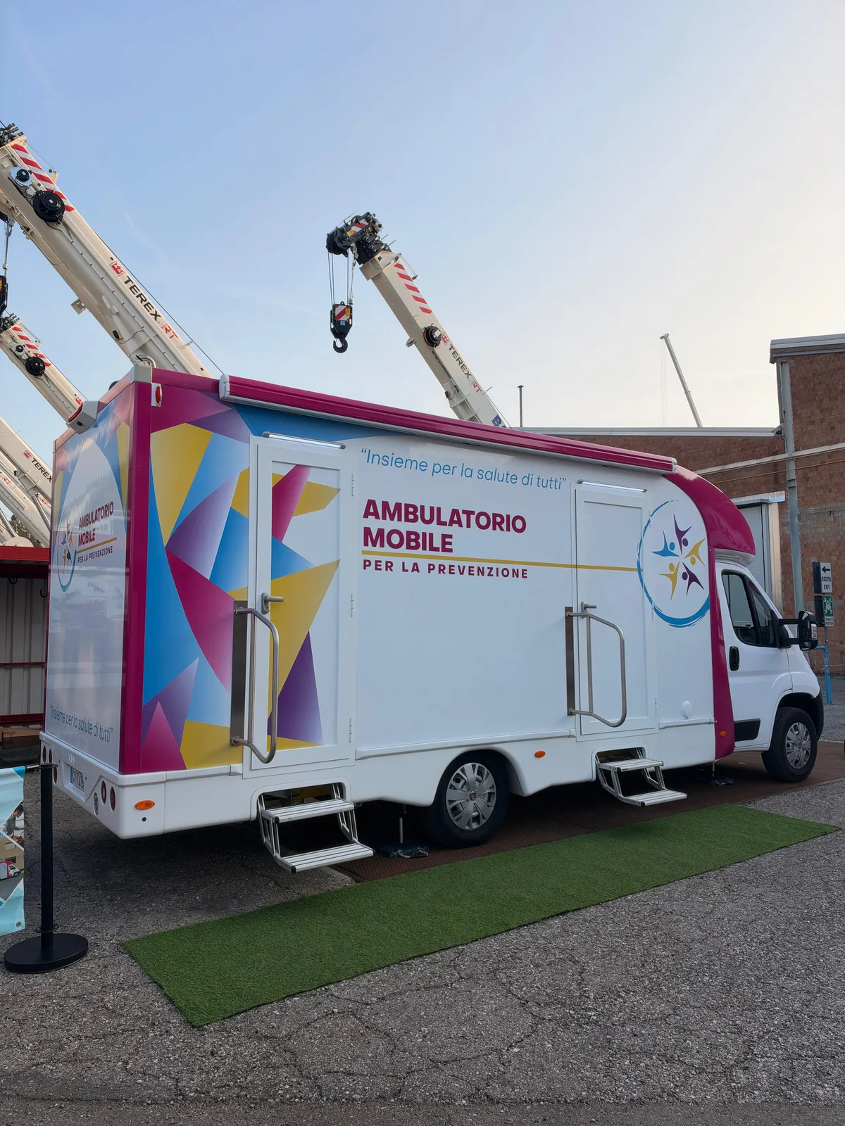 L'ambulatorio mobile di Clinica Mobile nel piazzale di RT Cranes con una gru alle spalle