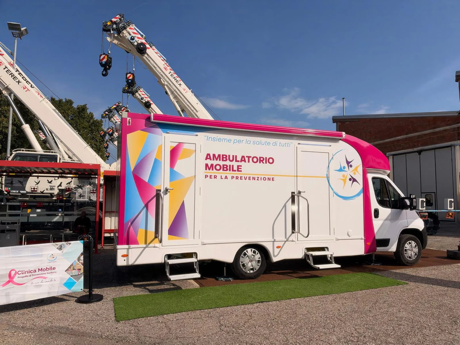 L'ambulatorio mobile, l'arco rosa e le gru di RT Cranes nel piazzale di Crespellano