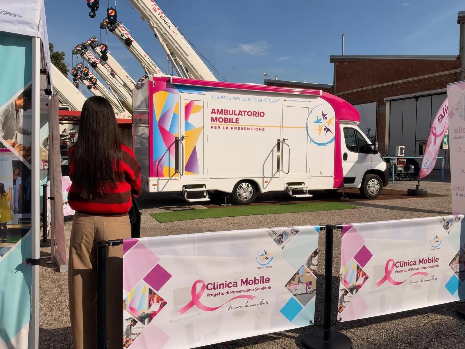 Una dipendente di RT Cranes alla barriera rosa con l'ambulatorio mobile e l'arco alle spalle