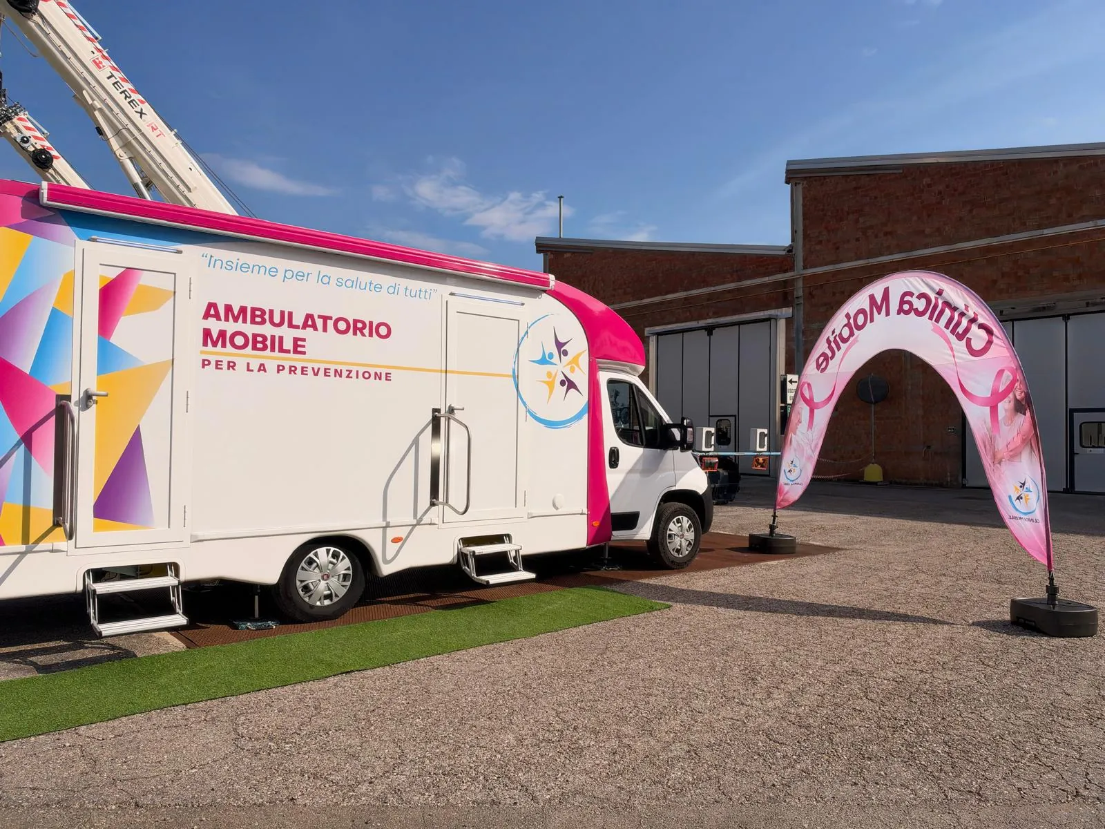 L'ambulatorio mobile di Clinica Mobile e l'arco rosa nel piazzale di RT Cranes a Crespellano
