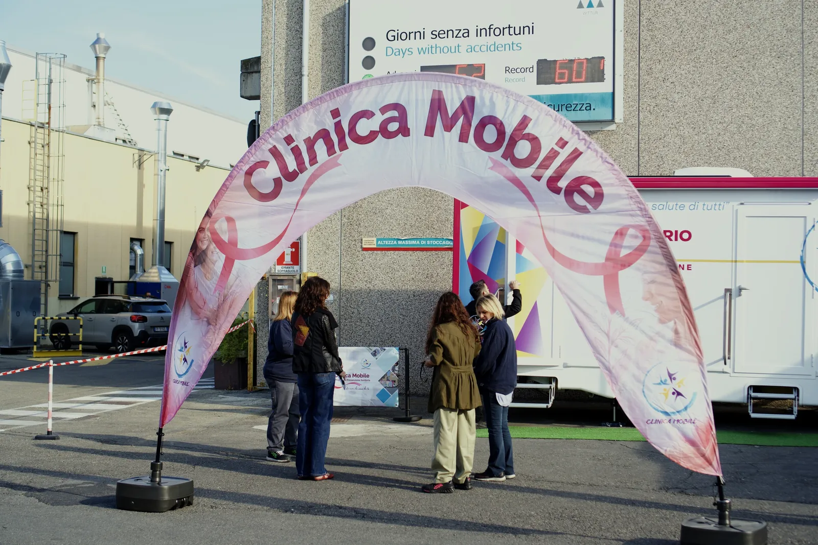 Dipendenti di Wittur sotto l'arco rosa di Clinica Mobile davanti all'ambulatorio
