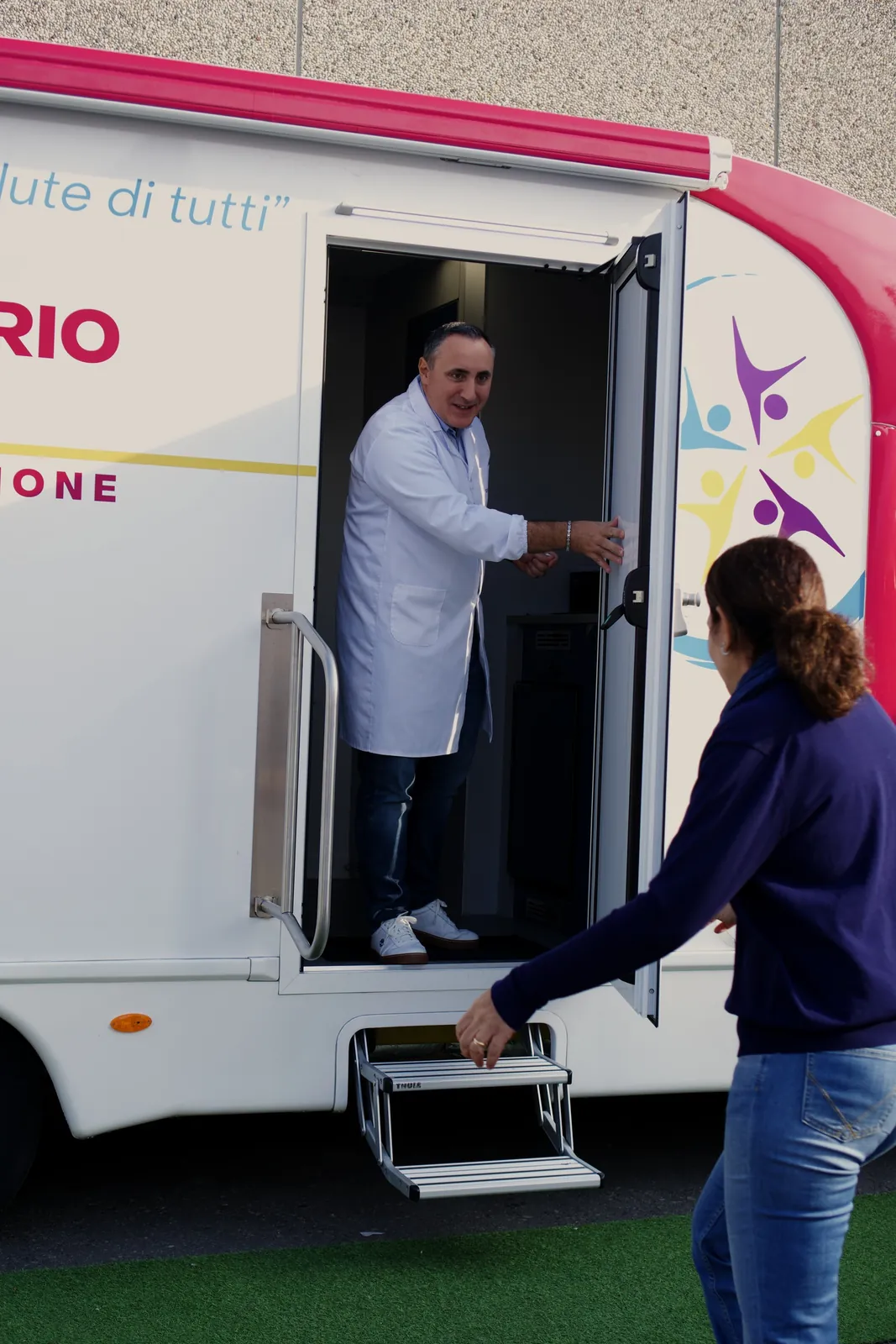 Il medico in camice accoglie una dipendente sulla porta dell'ambulatorio mobile