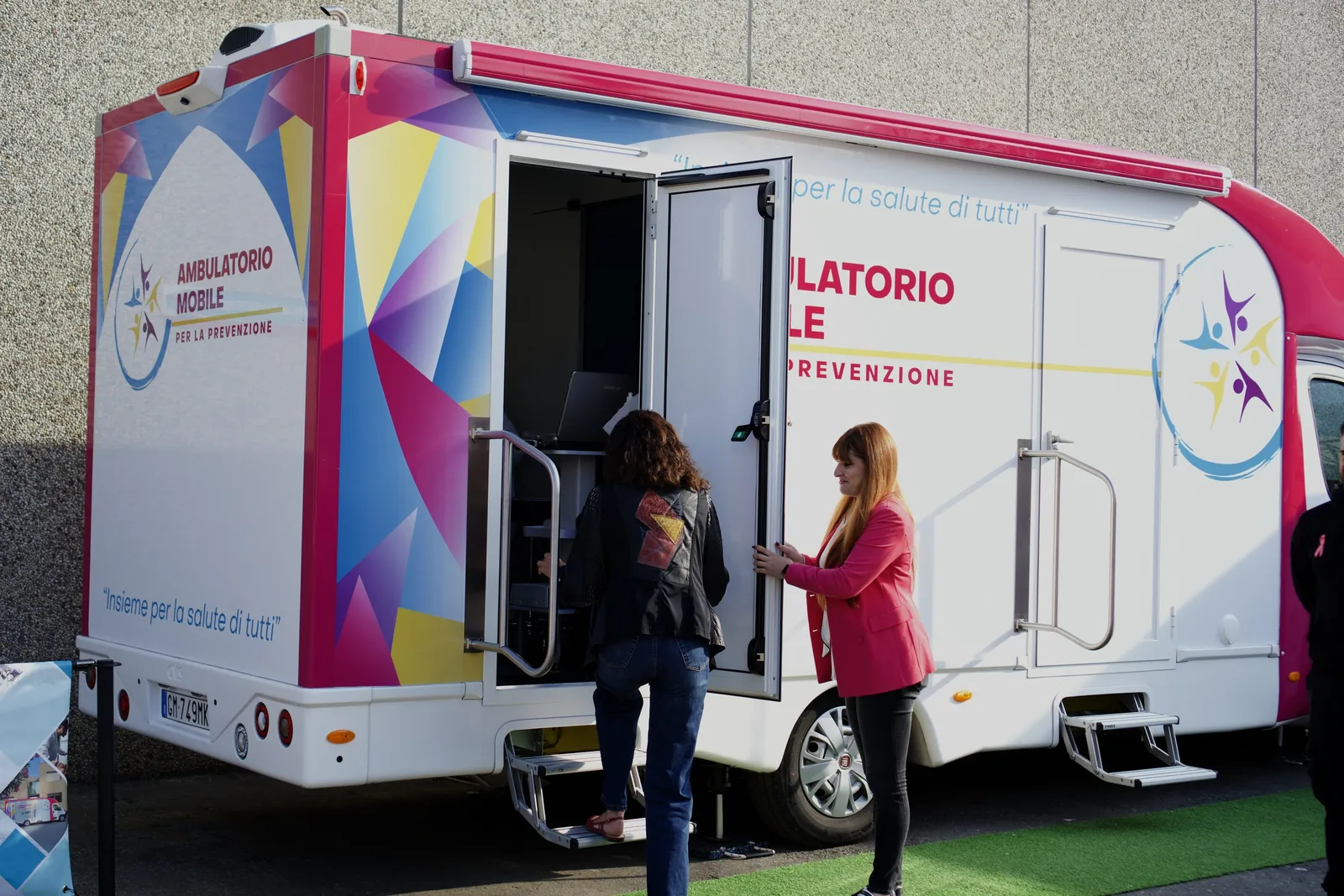 Una dipendente sale sull'ambulatorio mobile, accompagnata da un'operatrice in rosa